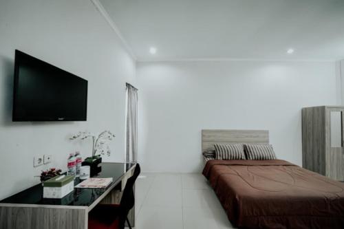 Dormitorio con cama, escritorio y TV en DPARAGON MT HARYONO en Semarang