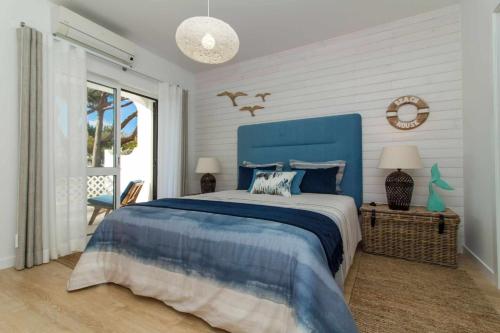 - une chambre avec un lit bleu et une tête de lit bleue dans l'établissement Beach House Apartment - Luxurious & Pool View & Golf & Tennis Court, à Albufeira