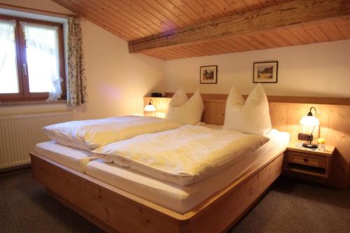 a bedroom with a large bed with white sheets at Ferienwohnung Neuhausen in Schönau am Königssee