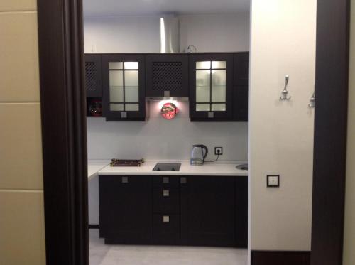a kitchen with black cabinets and a white counter top at Phan Thiet Apartments однокомнатные апартаменты с отдельной спальней in Velikiy Novgorod