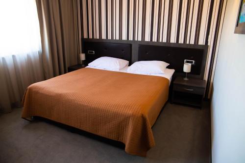 a bedroom with a large bed with an orange blanket at Art Hotel in Slavonski Brod