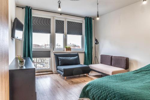 a bedroom with a bed and a chair and a window at Apartament Loft in Giżycko