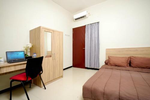 a bedroom with a bed and a desk and a chair at DPARAGON SONGGOLANGIT in Malang