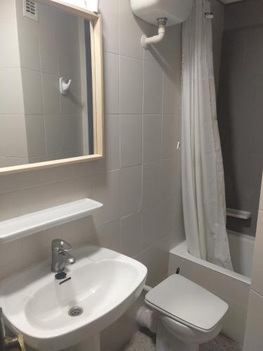 a bathroom with a sink and a toilet and a mirror at Apartamento Parchís con piscina in Denia