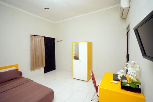 Schlafzimmer mit einem Bett, einem Schreibtisch und einem TV in der Unterkunft DPARAGON DWIKORA in Palembang