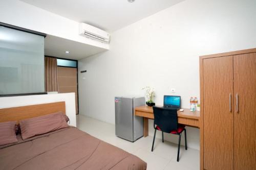 a bedroom with a bed and a desk with a laptop at DParagon Veteran in Banjarmasin