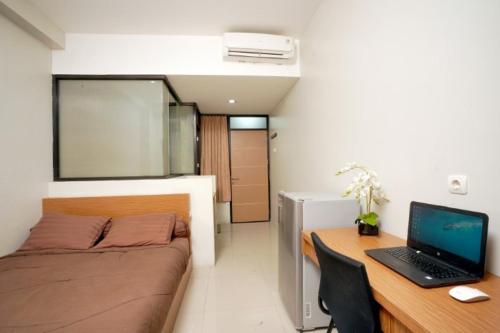 a bedroom with a bed and a desk with a laptop at DParagon Veteran in Banjarmasin