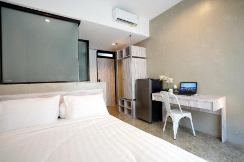 sypialnia z białym łóżkiem i biurkiem z komputerem w obiekcie DPARAGON KEBON JERUK w Dżakarcie