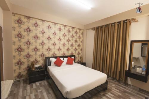 a bedroom with a white bed with red pillows at Newest Deluxe BnB, Ranee BNB in Shillong