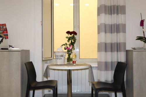 那不勒斯Hermes rooms for tourists的一张桌子,花瓶和两把椅子