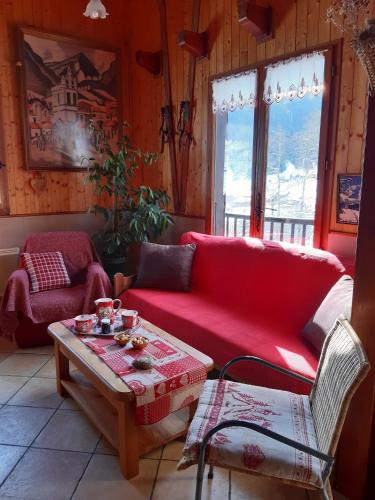 un salon avec un canapé rouge et une table dans l'établissement Le nid d'aigle, à Arêches