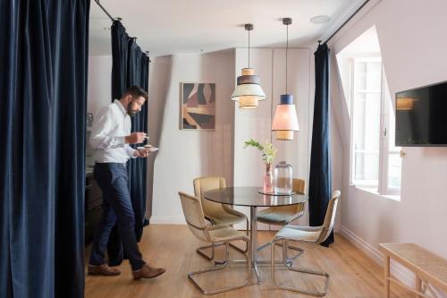 a man looking at his cell phone in a dining room at MiHotel Gailleton in Lyon