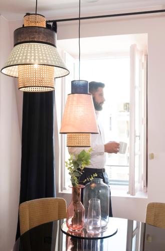 a man standing behind a table with three lights at MiHotel Gailleton in Lyon