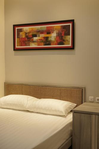 a bedroom with a bed with a picture on the wall at DJURAGANKAMAR PRIORITYINN in Solo