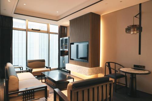 a living room with a couch and a tv at Sofitel Hangzhou Yingguan-Olympic Center Hotel in Hangzhou