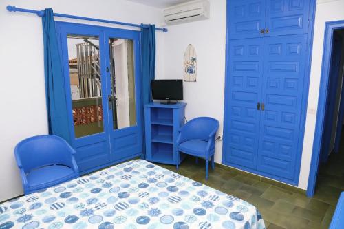 Schlafzimmer mit blauen Türen, einem Bett und einem TV in der Unterkunft Pensió Solivent in L'Escala