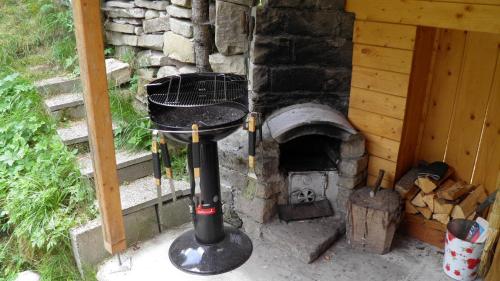 an outdoor grill with a smoker next to a stone oven at Apartmány pri Studničke in Oravský Biely Potok