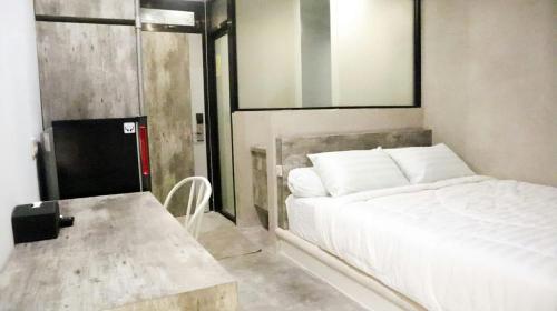 1 dormitorio con cama blanca y mesa en DJURAGANKAMAR GUNUNG ANYAR en Surabaya