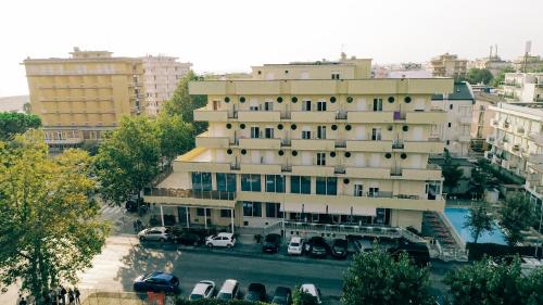 a large building with cars parked in a parking lot at Hotel Beverly in Rimini