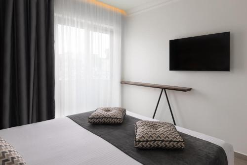 a bedroom with a bed with a television on the wall at Elakati Luxury Boutique Hotel - Adults Only in Rhodes Town