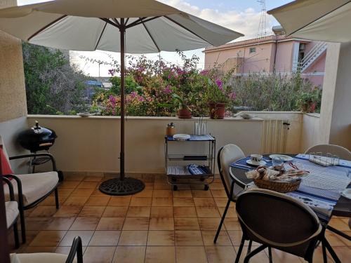 a patio with an umbrella and a table and chairs at Casa alla Guitgia 2 in Lampedusa