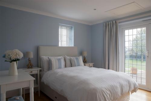 a bedroom with a white bed and a window at Moss Cottage in Bickley