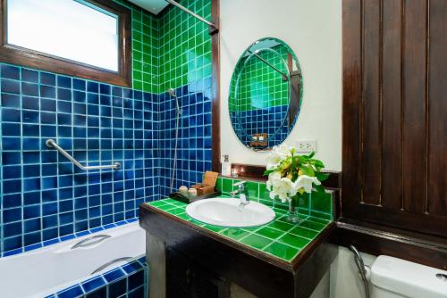 a bathroom with a sink and a mirror and a tub at Legendha Sukhothai Hotel in Sukhothai