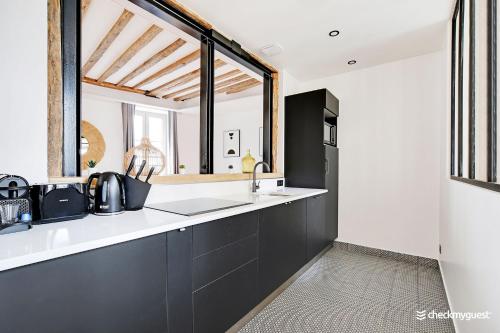 une cuisine avec comptoirs en noir et blanc et une fenêtre dans l'établissement CMG Résidence République II - Rue Béranger, à Paris