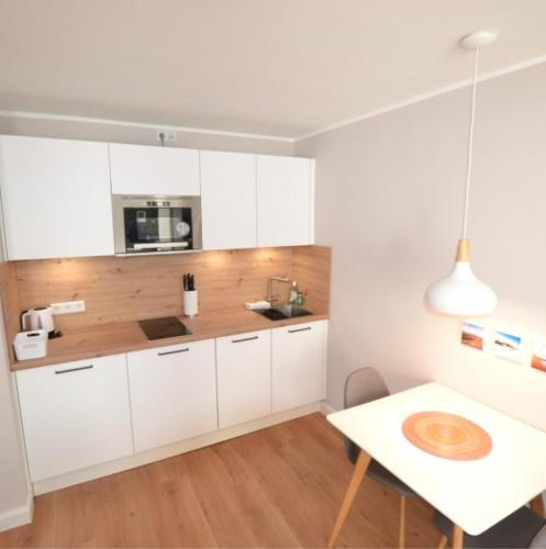 cocina con armarios blancos y mesa en Appartement-5-Kurviertel, en Westerland