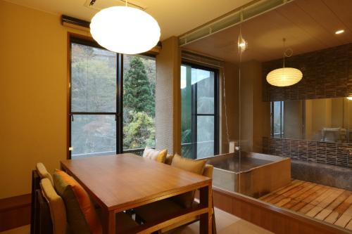a dining room with a table and a kitchen at Hakone Nanase formerly known as Manatei Hakone in Hakone