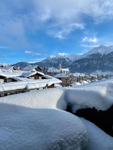 a group of snow covered roofs with mountains in the background at Mira Piz Signina - Wunderbare Dachwohnung mit Blick in die Berge in Laax
