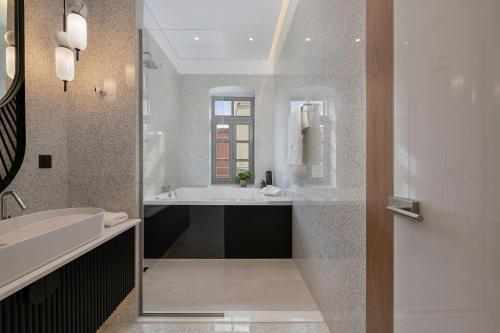 a bathroom with a tub and a sink and a mirror at Malmo Historic Hotel in Chania Town