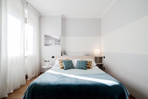 Dormitorio blanco con cama grande con almohadas azules y naranjas en Domus - byMyHomeinComo, en Como
