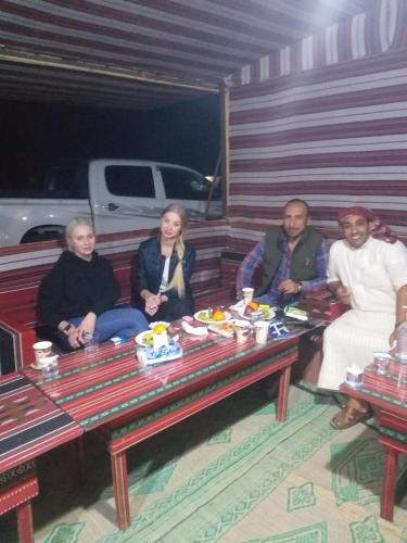 um grupo de pessoas sentadas num banco numa sala em مخيم الجبال البرونزية em Wadi Rum