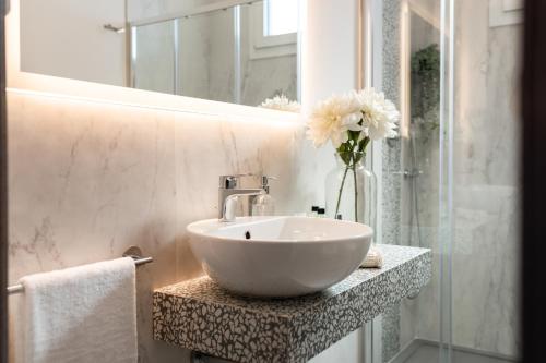 a bathroom with a white sink and a vase of flowers at Romagna Suite Hotel in Gatteo a Mare