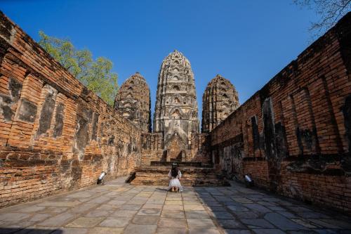 a dog sitting in front of a building at Le Charme Sukhothai Historical Park in Sukhothai