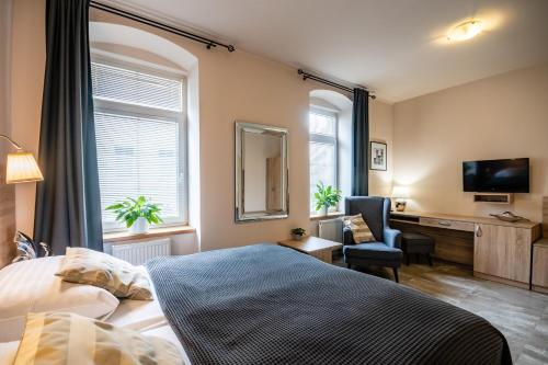 a bedroom with a bed and a desk and a television at Penzion a Restaurace Stará Roudná in Plzeň