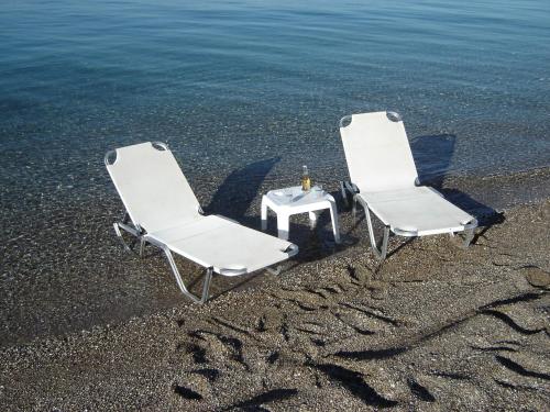 two white chairs and a table on the beach at Stavento in Diakopto