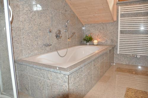 La salle de bains est pourvue d'une grande baignoire et d'une douche. dans l'établissement Almpartments Rosengasse, à Oberaudorf
