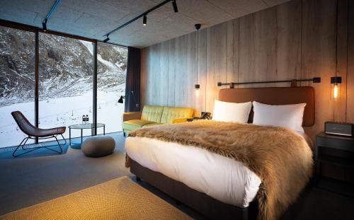 a bedroom with a bed and a chair and a window at Tenir Eco Hotel, Shymbulak Mountain Resort in Almaty