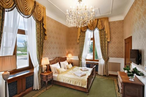 sypialnia z łóżkiem, żyrandolem i oknami w obiekcie Palac Mortegi Hotel & SPA- Restauracja Szlachecka, SPA, Basen, Sauny, Jazda Konna, Mini Zoo- Luksus, Relaks i Przyroda w jednym! w mieście Lubawa