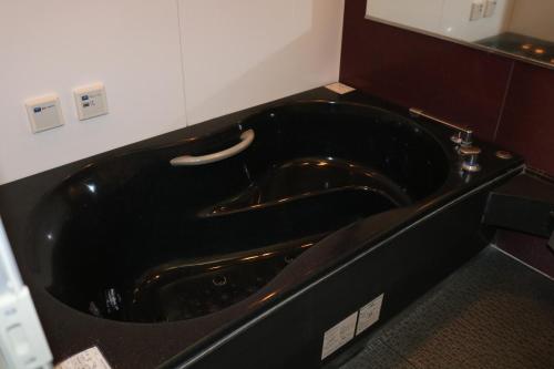 a black bath tub in a bathroom at Hotel Sunshine in Miyazaki
