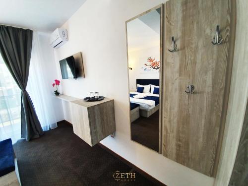 a bathroom with a mirror and a sink and a bed at ZETH HOUSE in Mamaia Sat/Năvodari