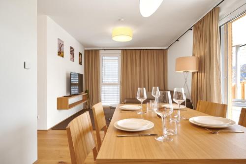 a dining room with a wooden table with wine glasses at Adler Lodge D1 by AA Holiday Homes in Tauplitz