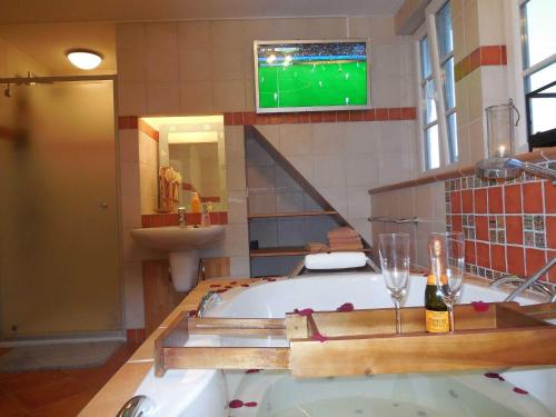 a bathroom with a tub and a tv on the wall at Landhausvilla Wolsroi in Steinbergkirche