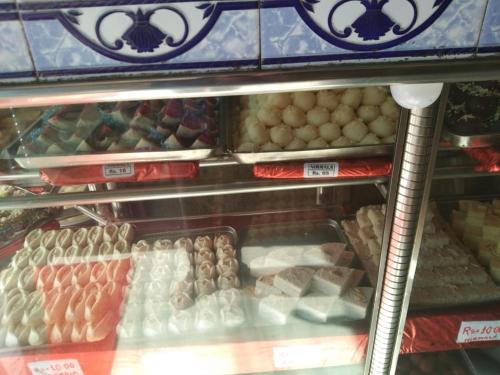 a display case filled with different types of food at Vamoose Nirmala in Kailāshahar