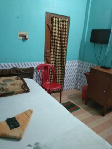 a bedroom with a bed and a red chair at Vamoose Nirmala in Kailāshahar
