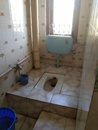 a bathroom with a toilet and a sink and a window at Vamoose Nirmala in Kailāshahar