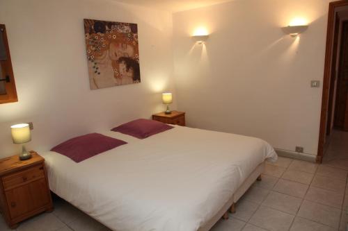 een slaapkamer met een groot wit bed met 2 lampen bij Chalet Bouquetin- Loir in Champagny-en-Vanoise