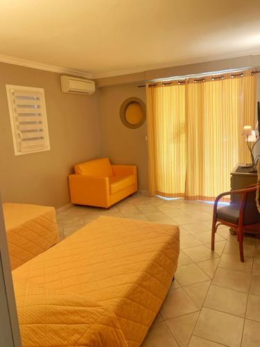 a hotel room with two beds and a chair at Hôtel Beau Soleil in Le Lavandou